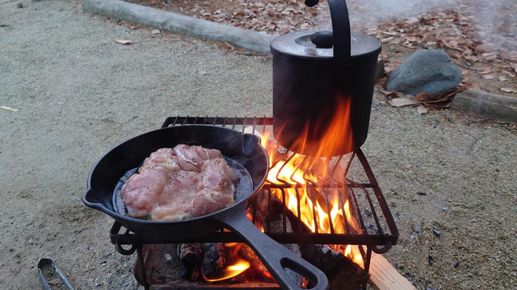 焚火で鶏肉をスキレットで焼く