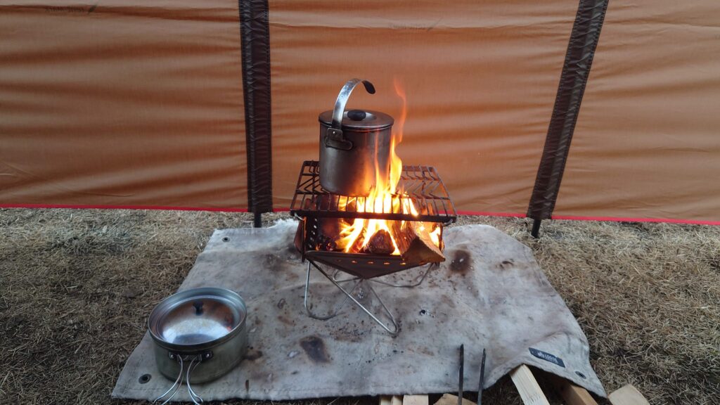 焚火シートを敷いた焚火と鍋やかん