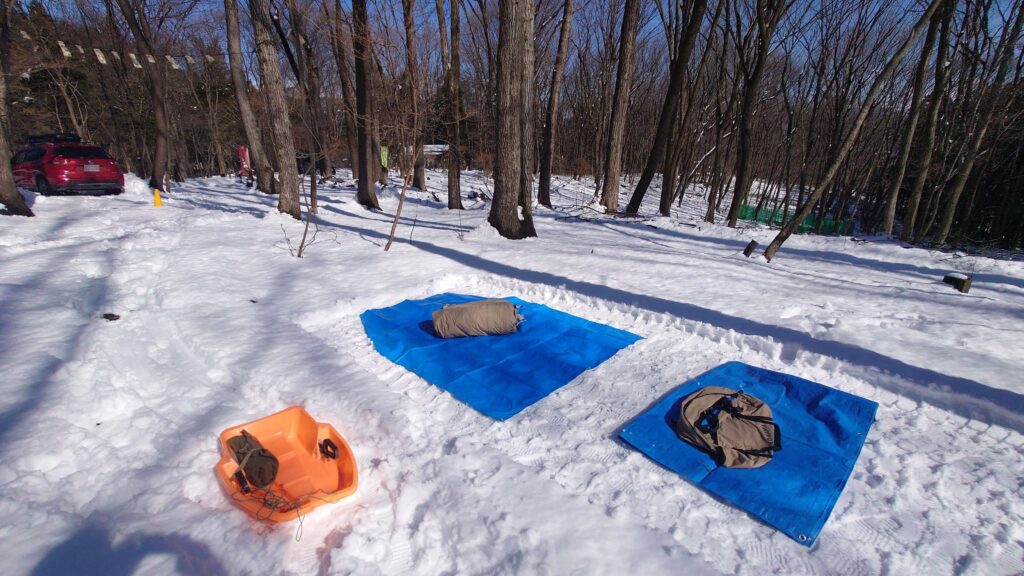 雪を踏み固めたキャンプサイトに広げたブルーシート