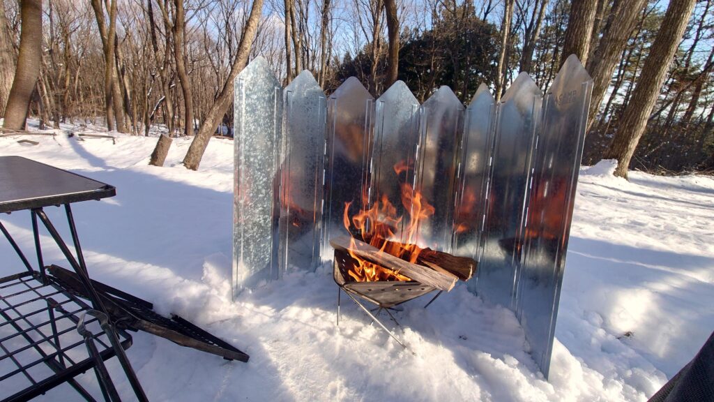 雪の中の金属製焚火スクリーンと焚火