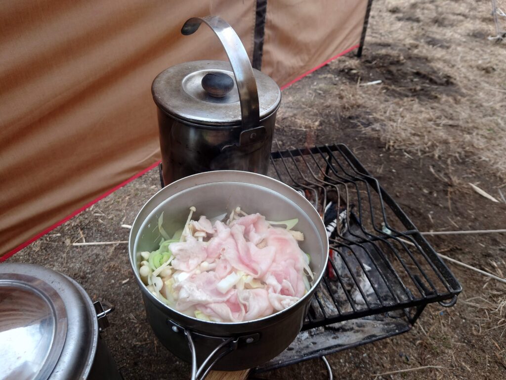 鍋を焚火で煮込む