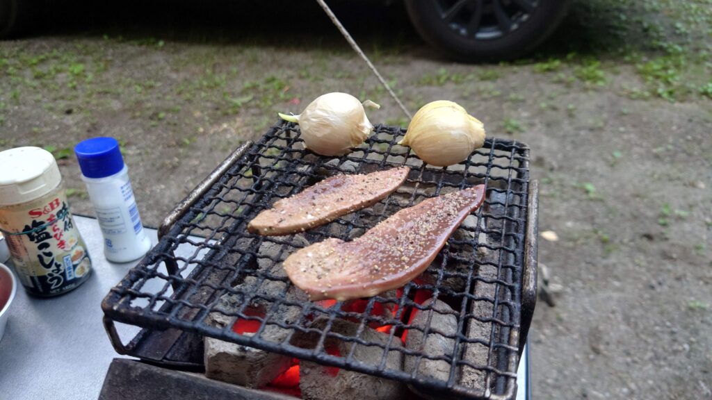 炭火でレバーとニンニクを焼く