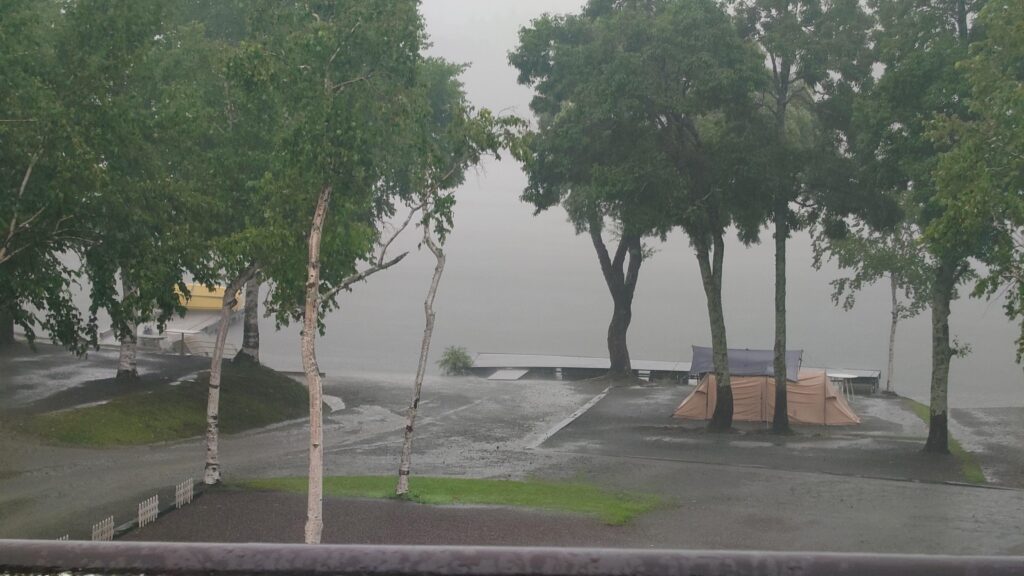 降り続く雨の中の湖畔サイト