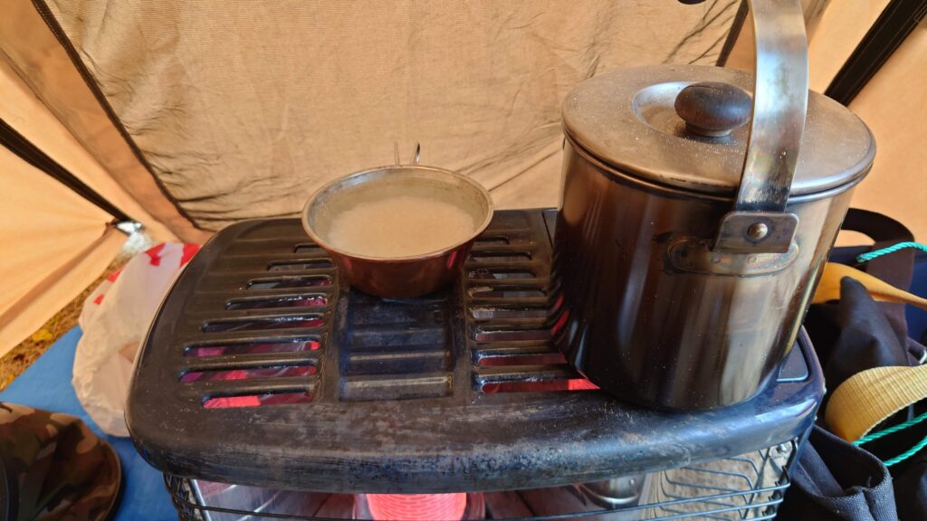 製油ストーブの上のシェラカップとケトル