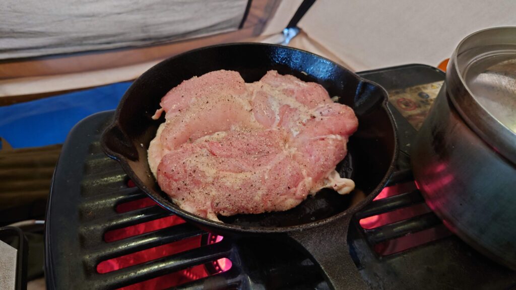 石油ストーブ上のスキレットで鶏モモ肉を焼く