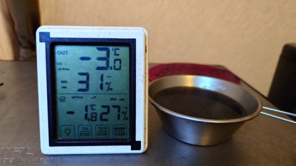 最低気温を示す温度計とシェラカップのコーヒー