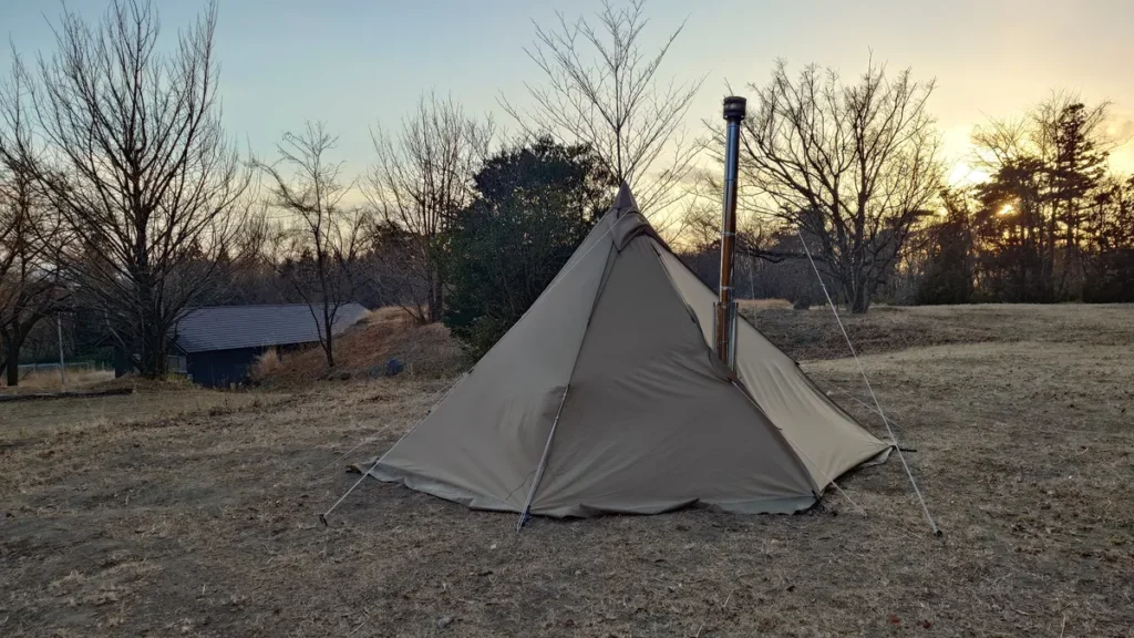煙突の吐出したワンポールテントと夕日