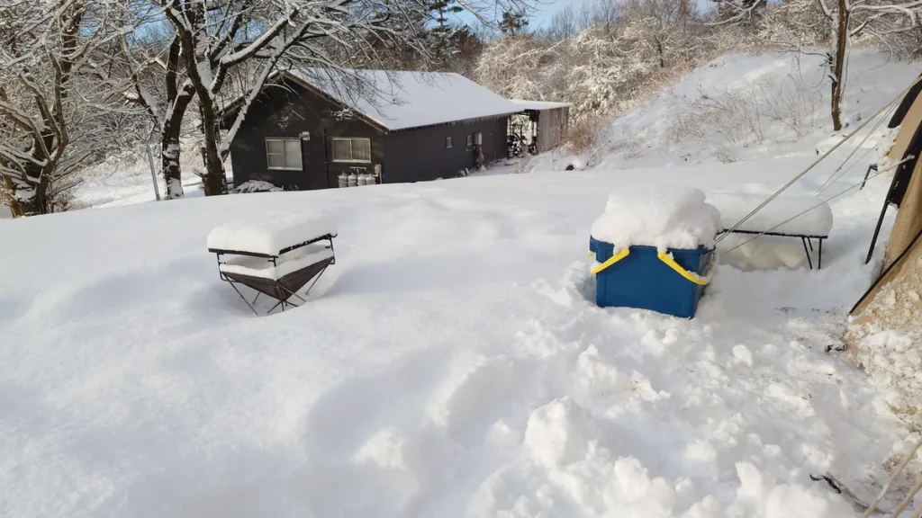 雪をかぶった焚火台と収納ボックス