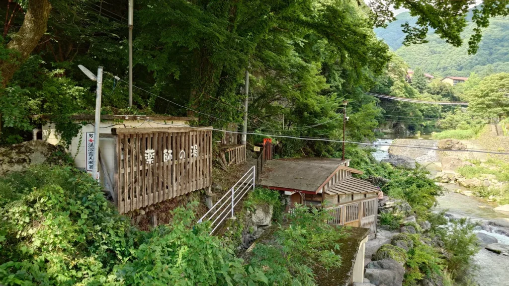 男鹿川薬師橋から見た上流と薬師の湯露天風呂施設