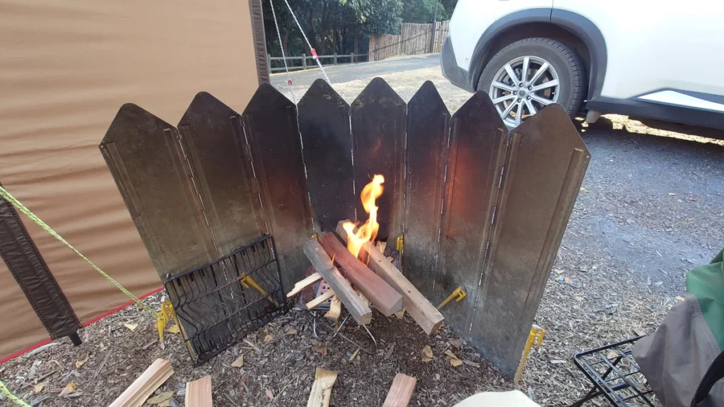 焚き火で長い薪を燃やす