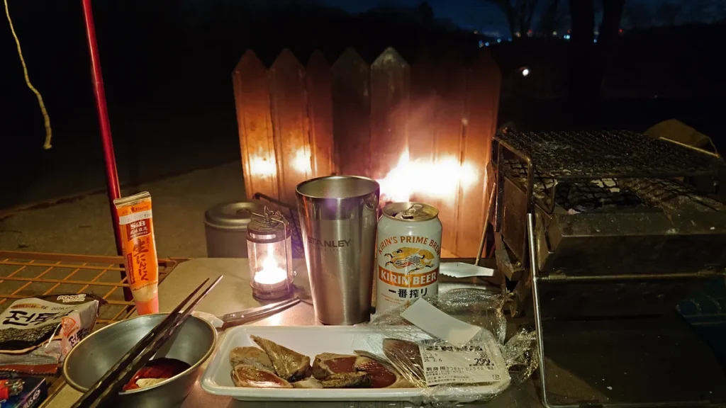 焚火スクリーンに反射する炎とビール