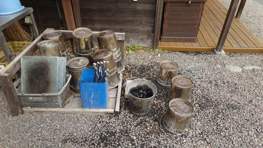 焚き火の灰や消し炭を回収するための水入りバケツと火ばさみ