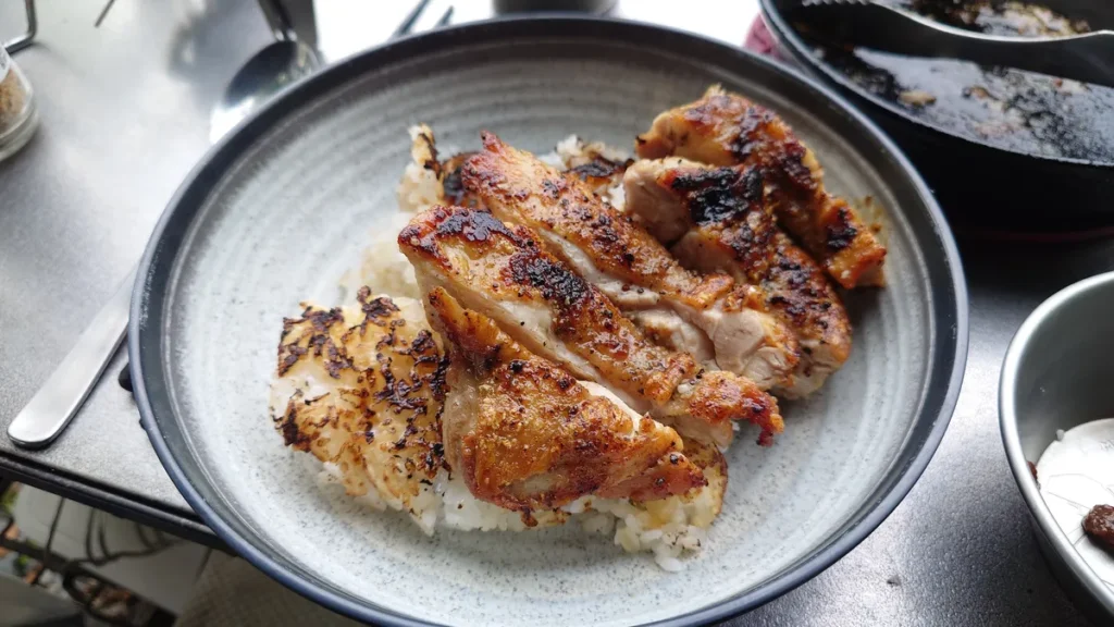 ご飯の上に載せた鶏ももステーキ